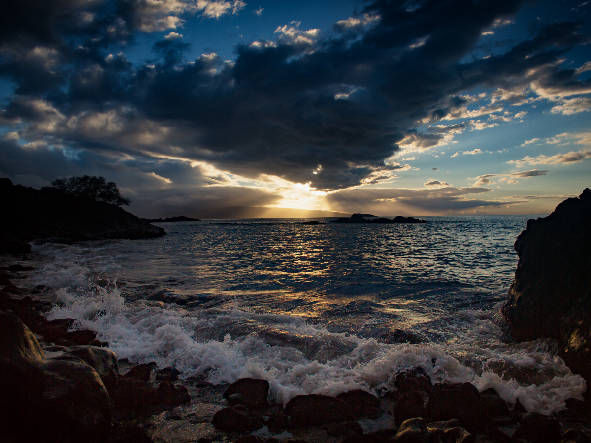 sunsetting in the Wailea Beach with waves crashing on the rocks