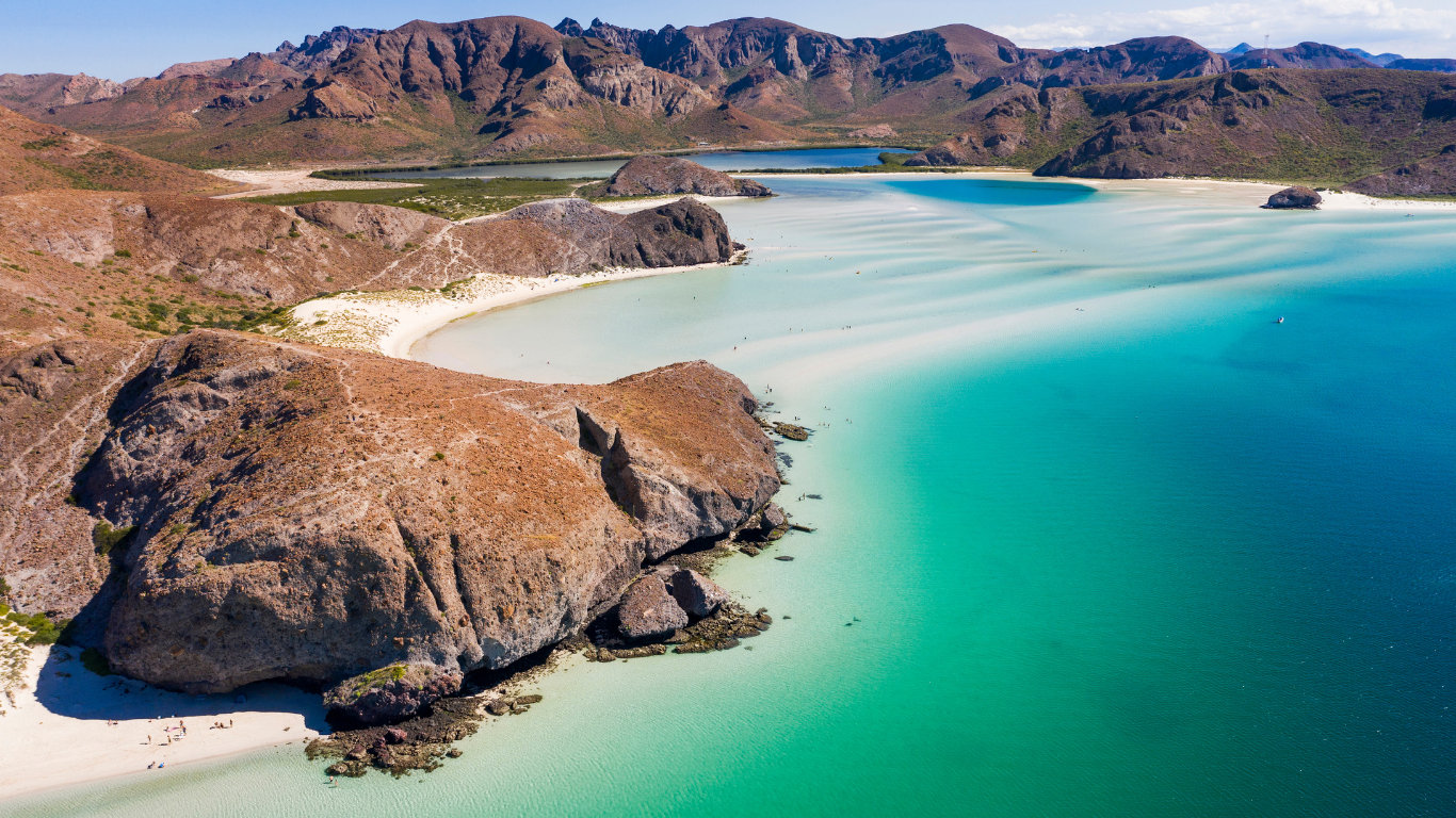 barren desert mountains with emerald green clear waters with sandy beaches along the mountain's at Balandra Beach, Mexico.