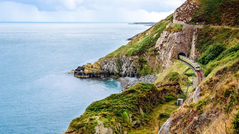 train running through the mountain near the ocean in Bray, Ireland