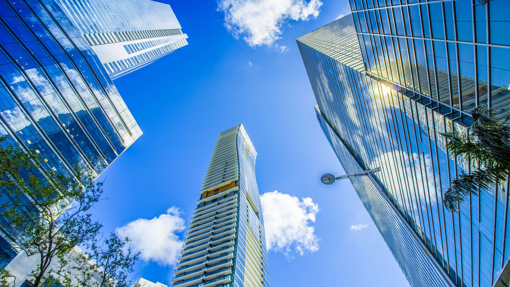 Skyscrapers in Brickell, Miami, reflecting the bright blue sky and sunlight, showcasing the modern urban architecture of the city's financial district.