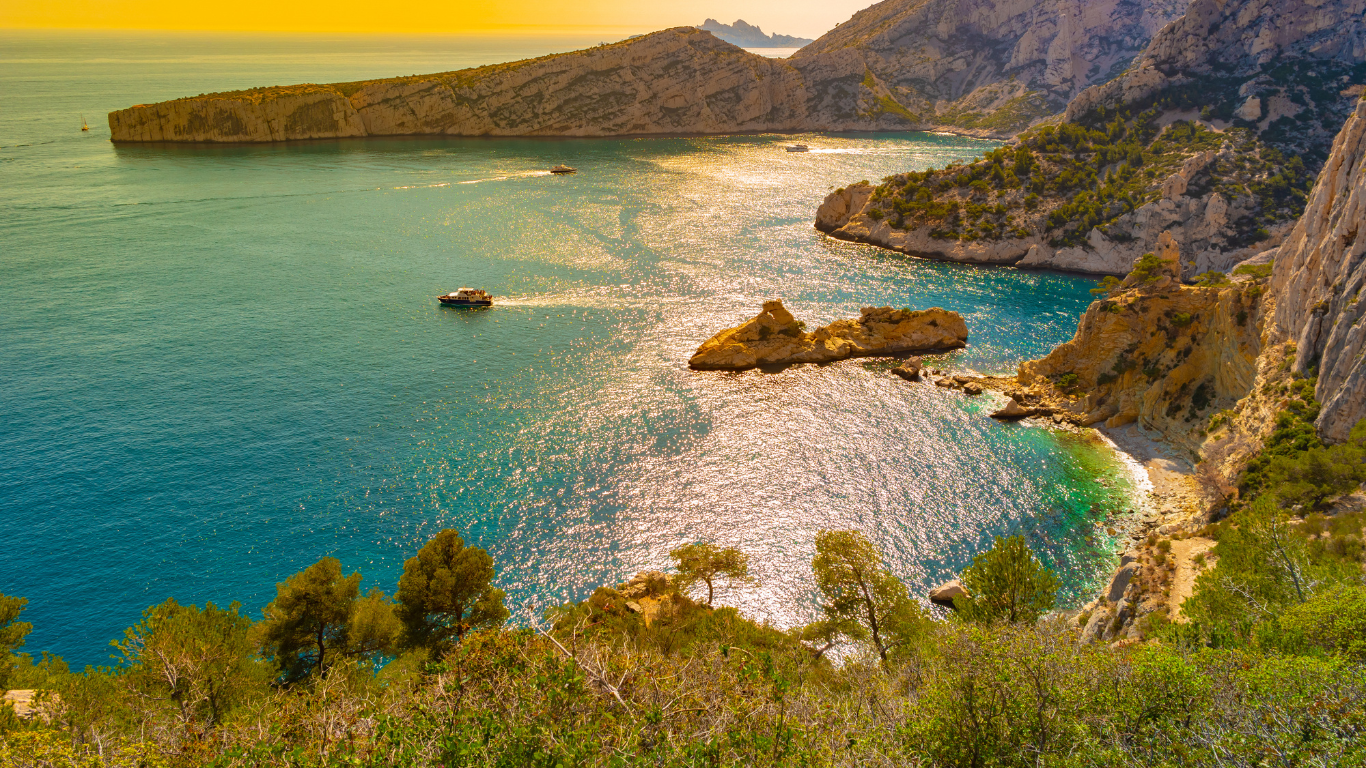 beautiful colored sea water with view of tall cliffs and a boater enjoying their day at Calanques National Park