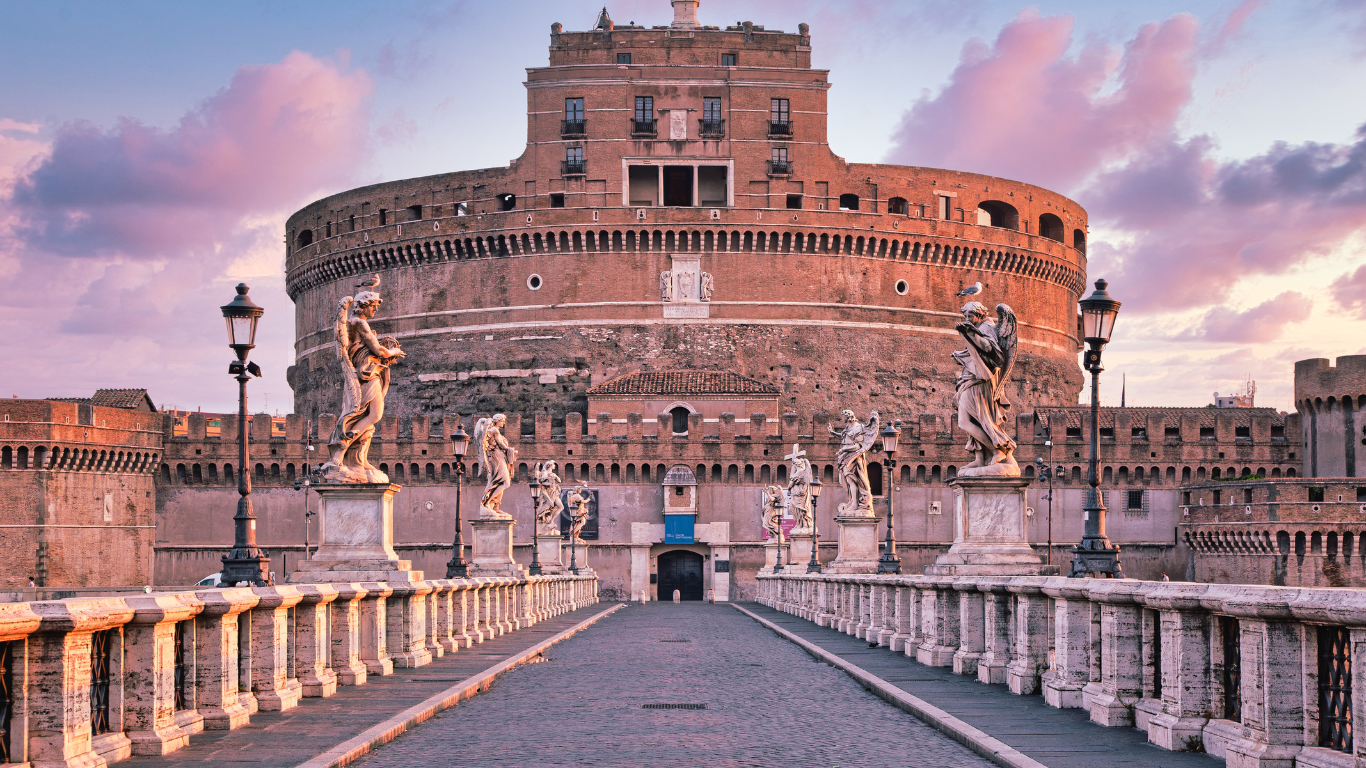 a massive cylindrical fortress with stone walls rising above the Tiber River. The castle is crowned by a statue of the Archangel Michael at the top, standing on a circular terrace. The bridge leading to the castle is lined with marble statues of angels, creating a dramatic and historic approach. The fortress's imposing structure contrasts with the elegant statues, offering a stunning view against the backdrop of the river and sky.