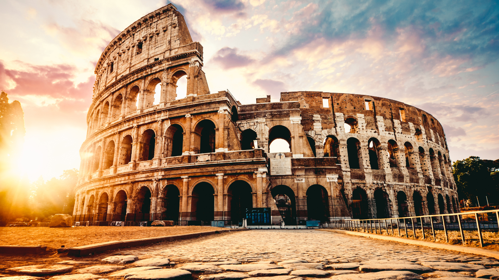 The Colosseum at sunset in Rome taken from ground level above cobblestone streets