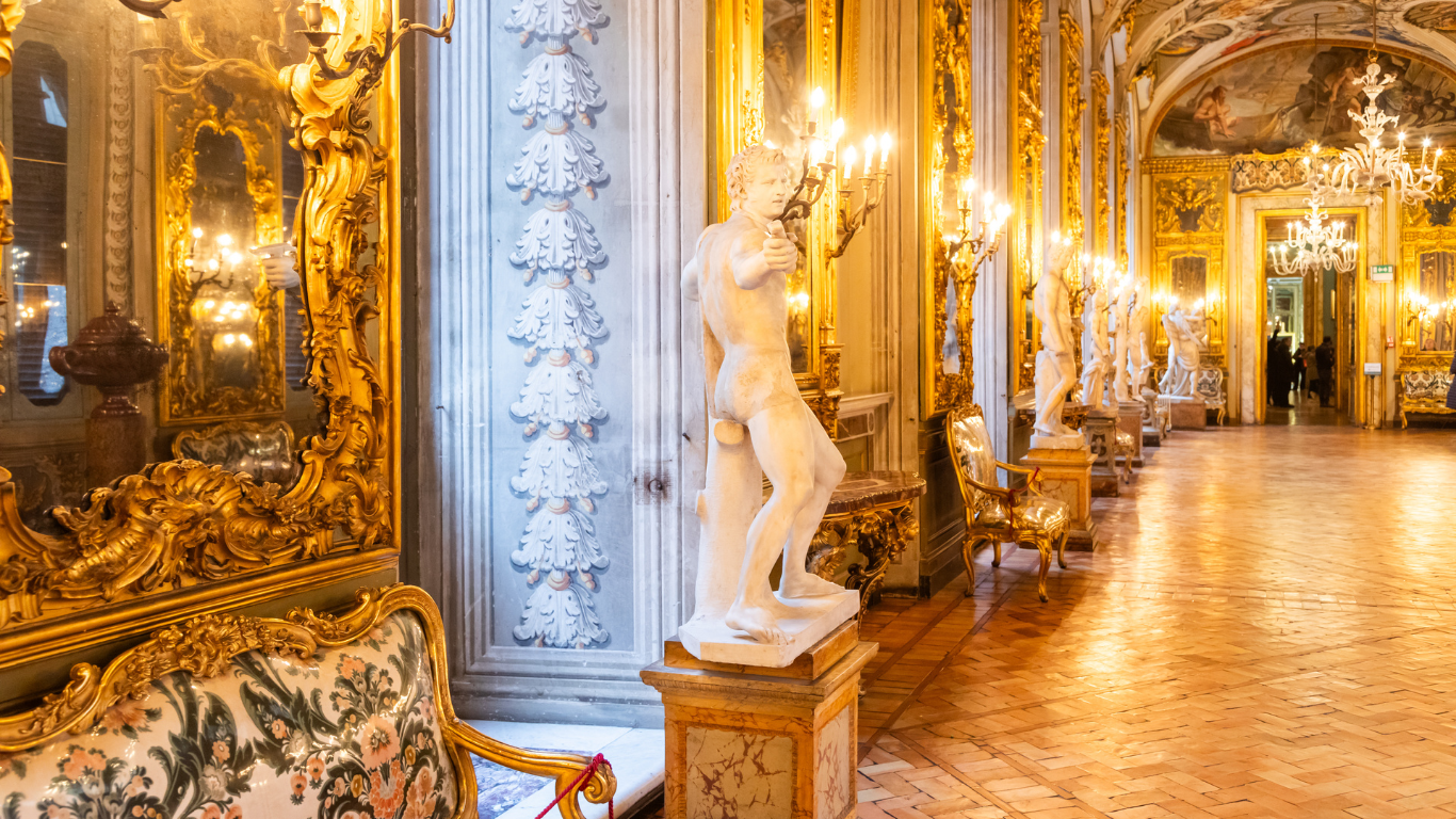 The long, ornate halls feature gilded frames, detailed frescoes on the ceilings, and lavish chandeliers. Walls are lined with an extensive collection of classical paintings and sculptures, with luxurious red and gold tones dominating the decor. The gallery’s elegant and grand atmosphere reflects its historical significance and the aristocratic heritage of the Doria Pamphilj family.