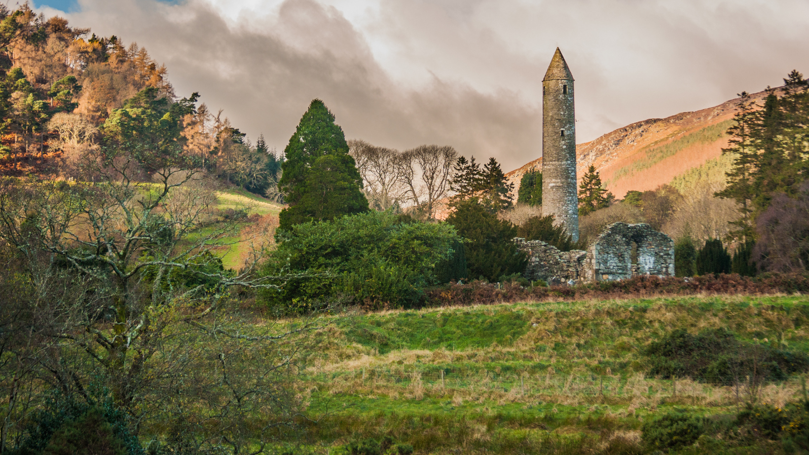 fall colors in a valley with ancient ruins surrounded by trees a the historical Glendalough site