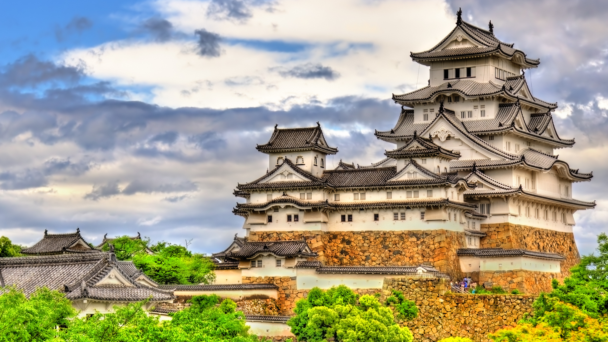 Himeji Castle in Japan, with its iconic white walls and multi-tiered roofs, standing majestically on a hill.