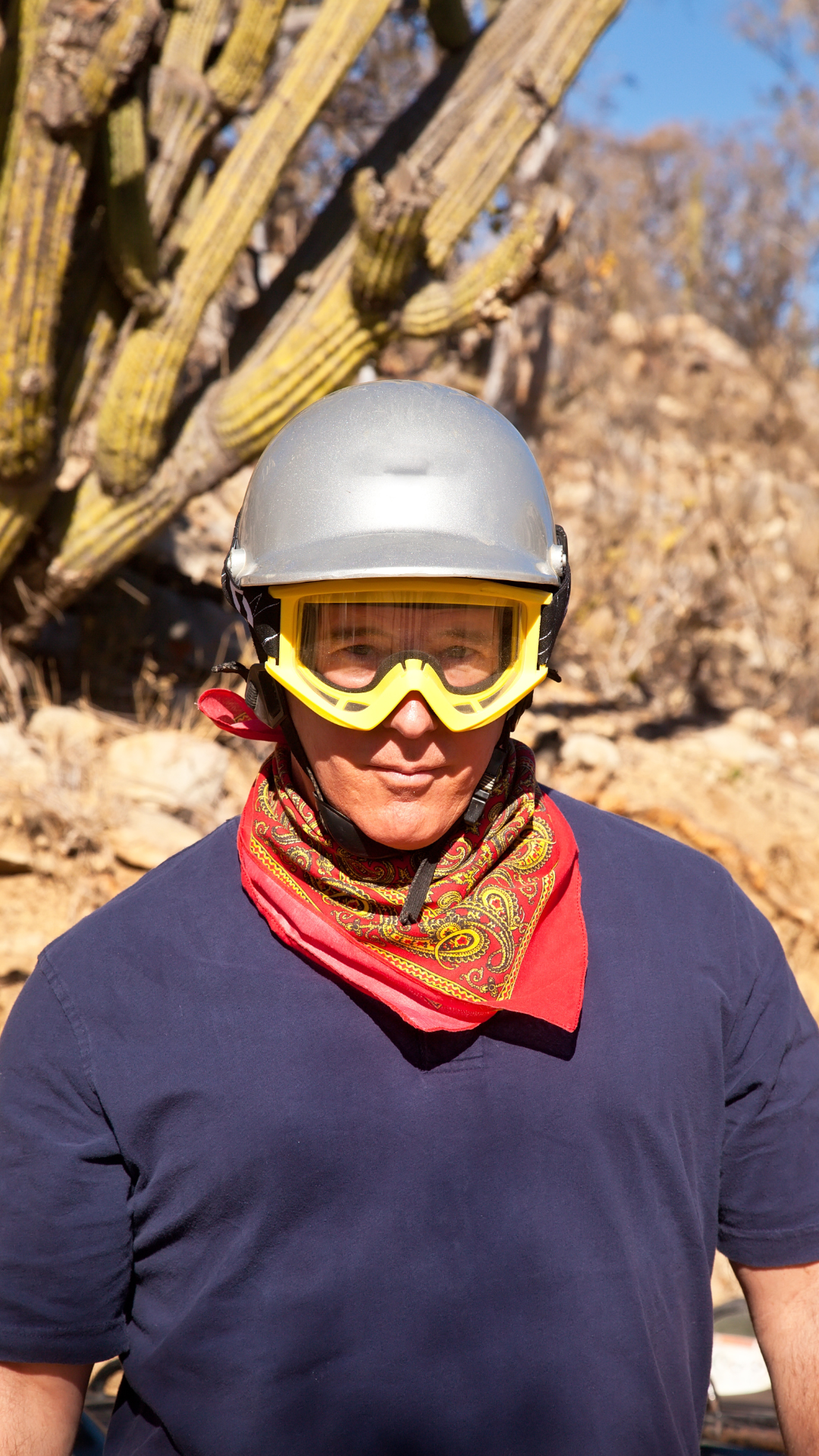 Man wearing a blue shirt and grey helmet with caucus behind him on an ATV tour in Aruba's Arikok National Park