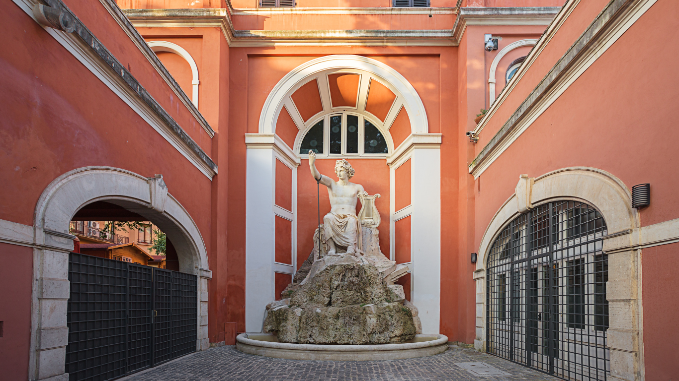 The building features large arched windows, decorative stone carvings, and columns framing the main entrance. The palace's exterior is elegant and imposing, with a spacious courtyard in front. Surrounded by manicured gardens, Palazzo Barberini reflects the opulence and artistic grandeur of 17th-century architecture, now housing the Galleria Nazionale d'Arte Antica.