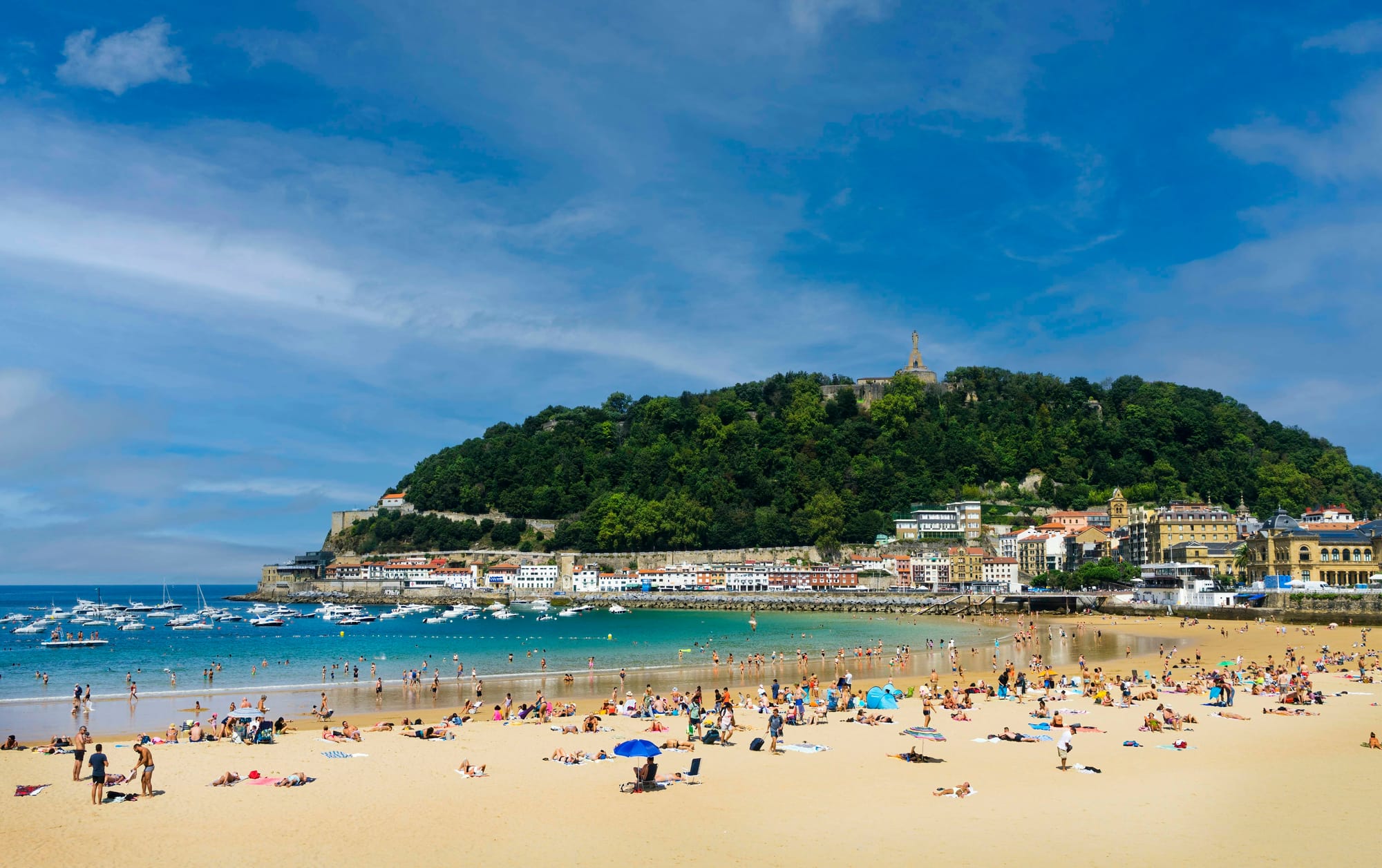 Plage de la Côte des Basques beach with beach goers catching some sun and boats and surfers in the water