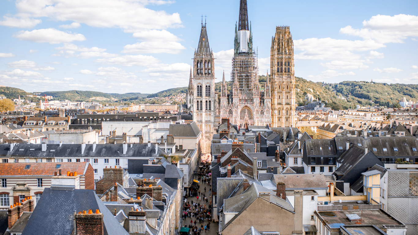 overlooking the city of Rouen, France with a large cathedral in the center of the town that towers over the rest of the cities buildings