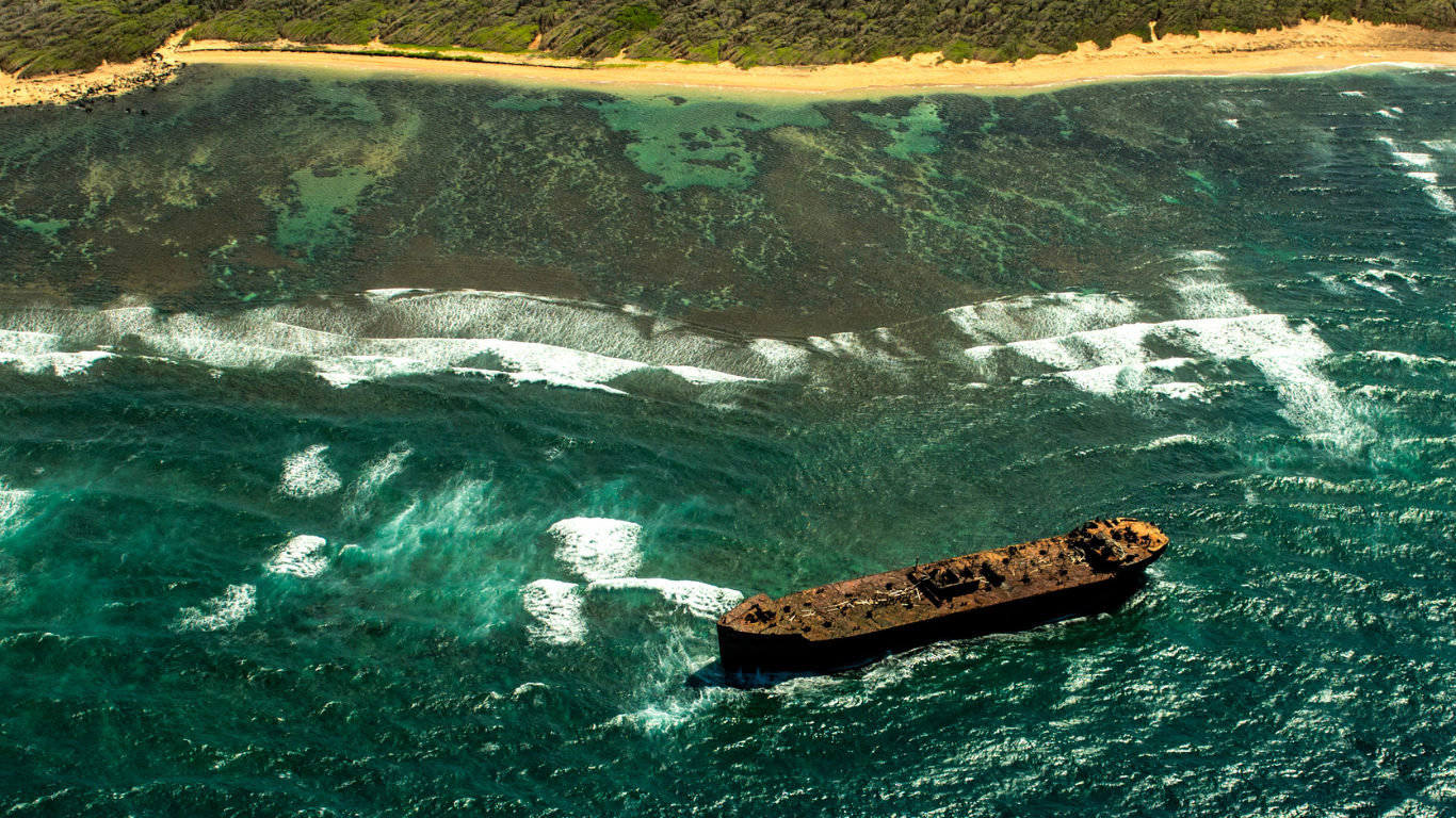 abandon rusted out tanker ship in front of a beach with clear turquoise waters at Ship Wreck Beach in Lanai, Hawaii.