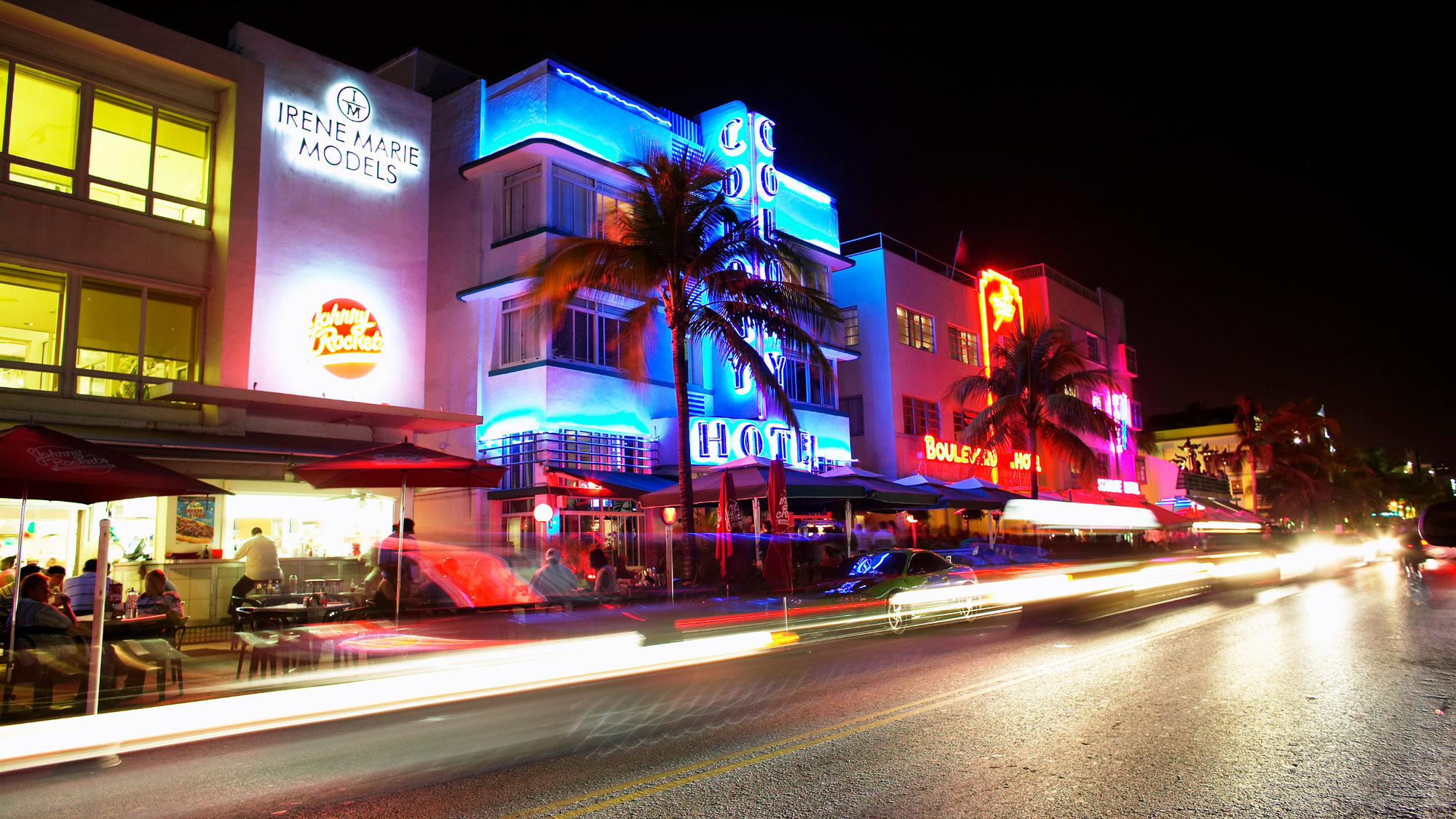 Neon-lit Art Deco buildings on Ocean Drive in South Beach, Miami at night, showcasing the lively nightlife with bustling cafes and bright lights.