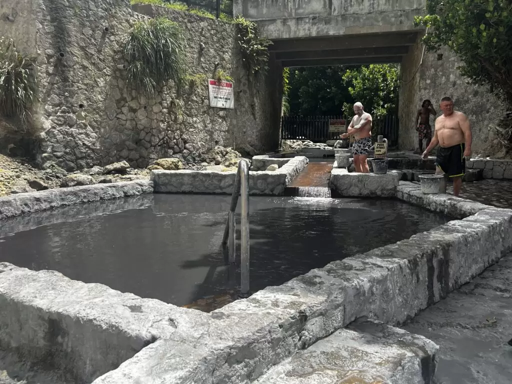 Sulphur Springs In St. Lucia shows two men about to climb into the springs that have manmade stone containment placed around them