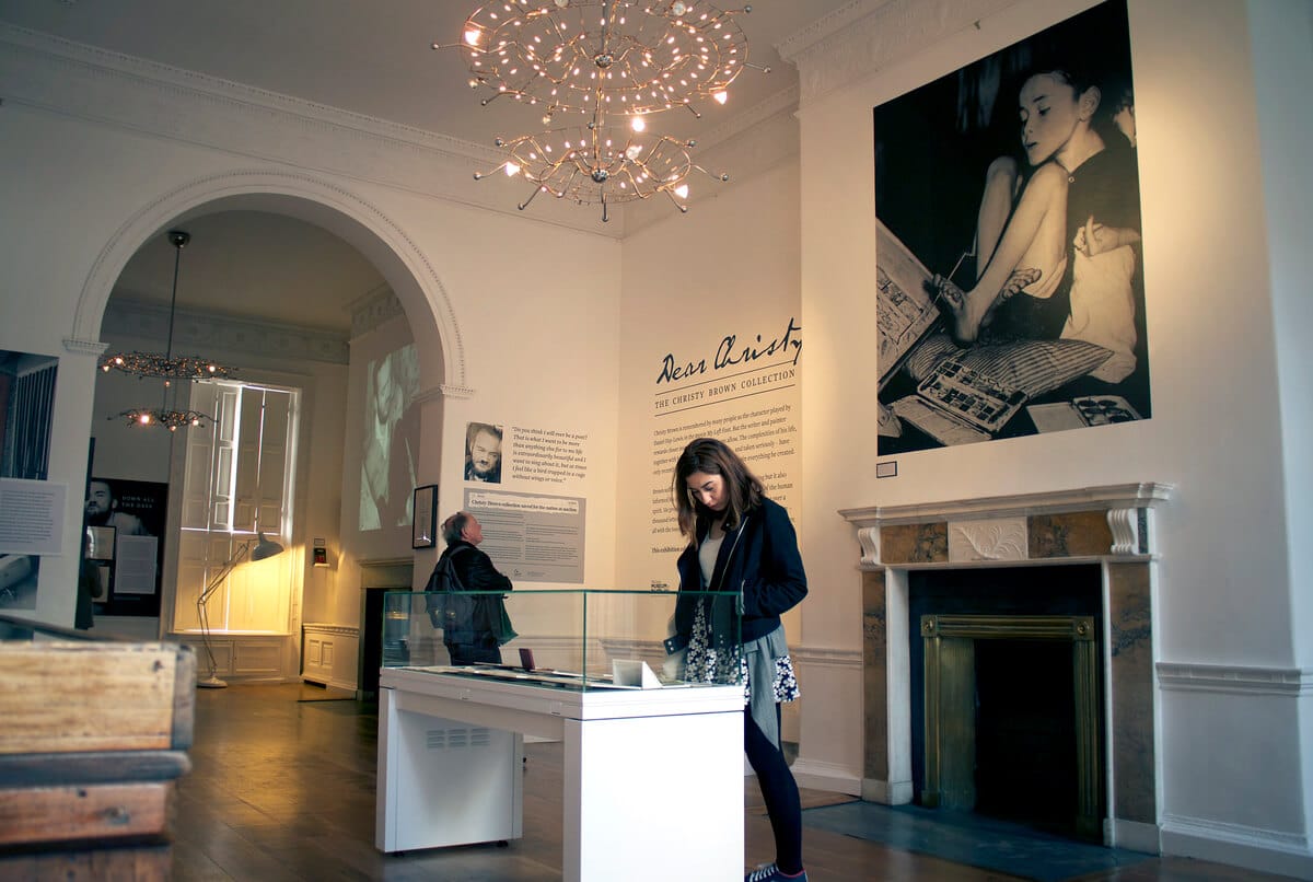 woman looking at a museum piece inside of a black and white room with a fireplace behind her at The Little Museum of Dublin