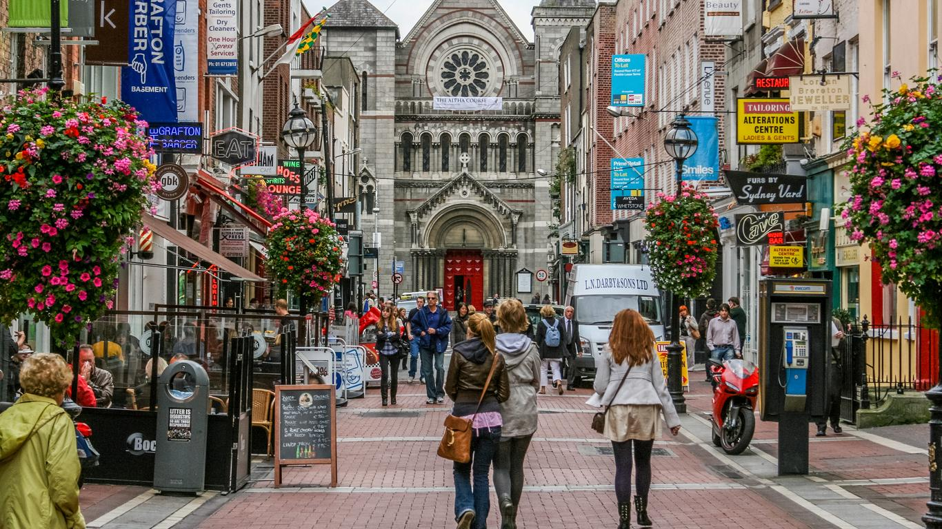 cobblestone streets surrounded by a downtown area with people walking and flowers along the streets on Grafton Street