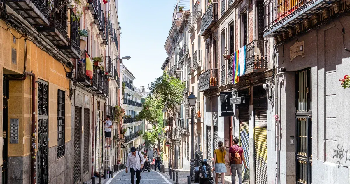 people walking between charming Spanish buildings in the Malasaña neighborhood In Madrid