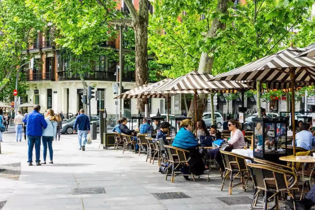 People out eating and enjoying their day at tables on the sidewalk in the Chamberí District in Madrid