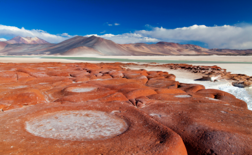 large red rocks with round circles on them and mountains in the background at Atacama Desert