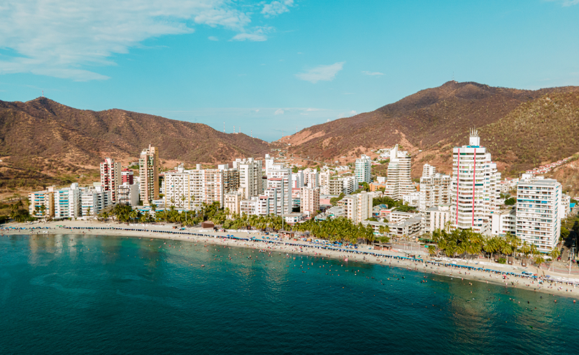 Sea and city view of Santa Marta Colombia, showing a bunch of tall white city buildings with mountains in the background of this beautiful city.