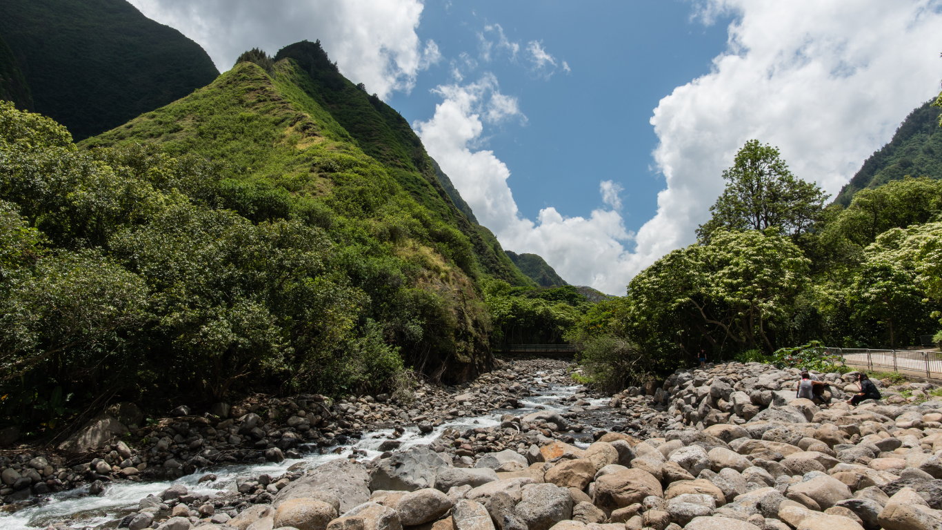 rocky creek with flowing water surrounded by lush green mountains at iao valley state park in Maui.