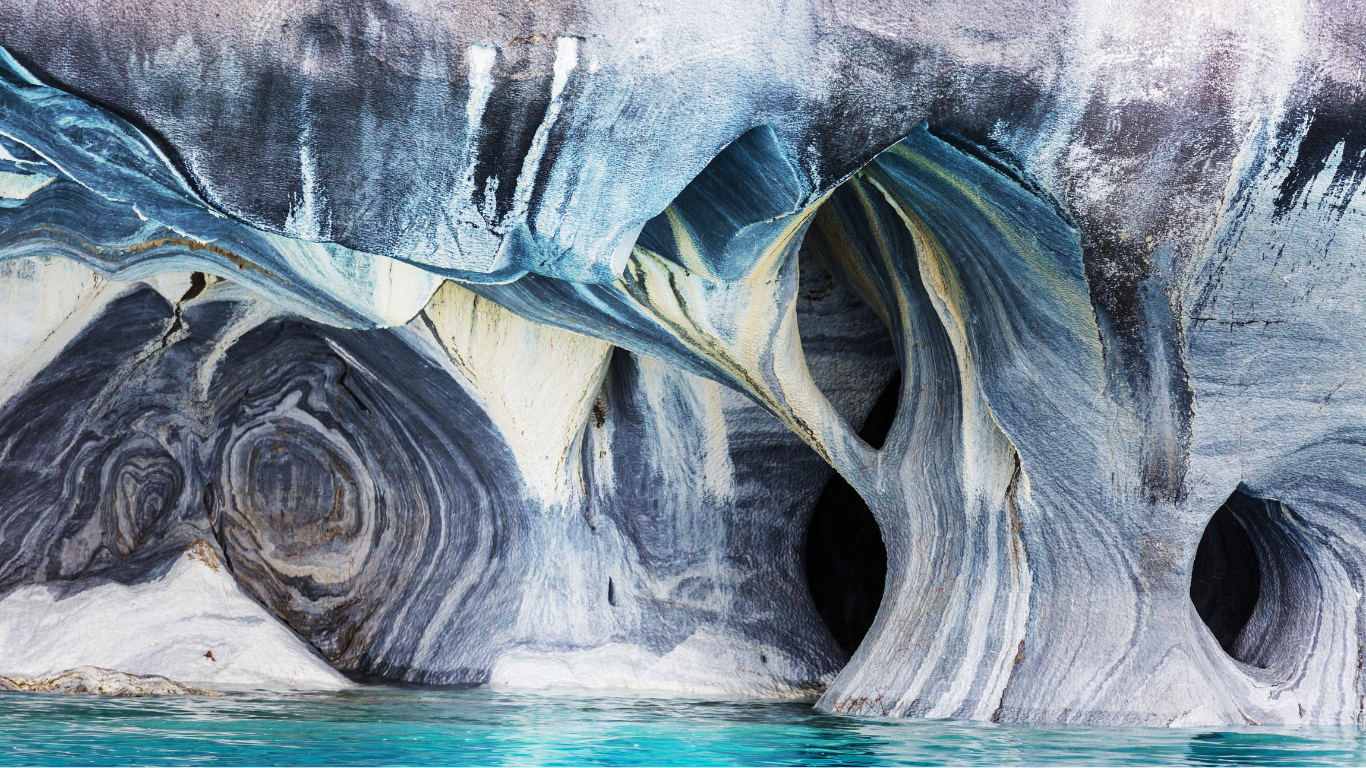 The Marble Chapel Section of the Marble Caves in Patagonia, shows rock with circular holes in them and clear blue water