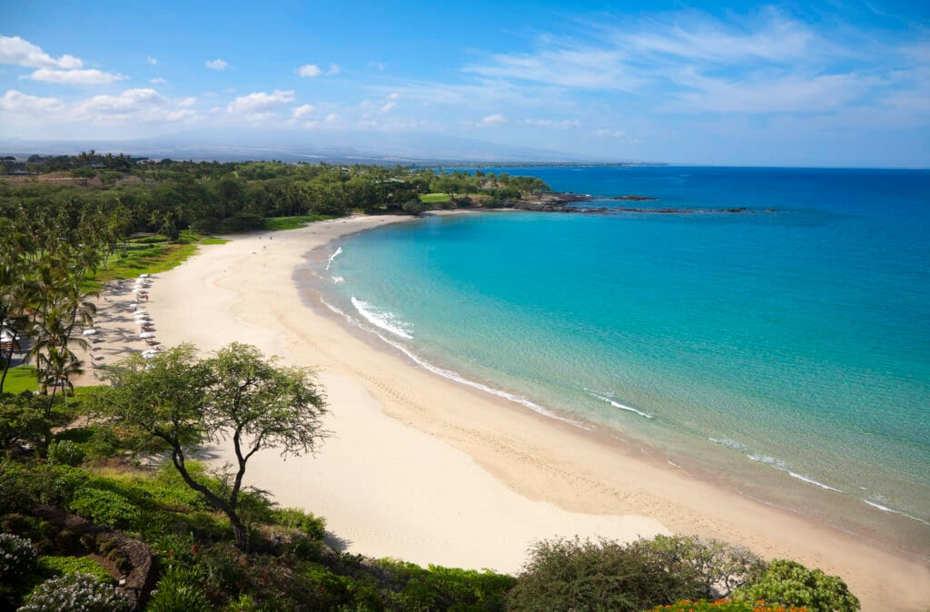 White sandy beach with calm clear blue waters at Mauna Kea Beach