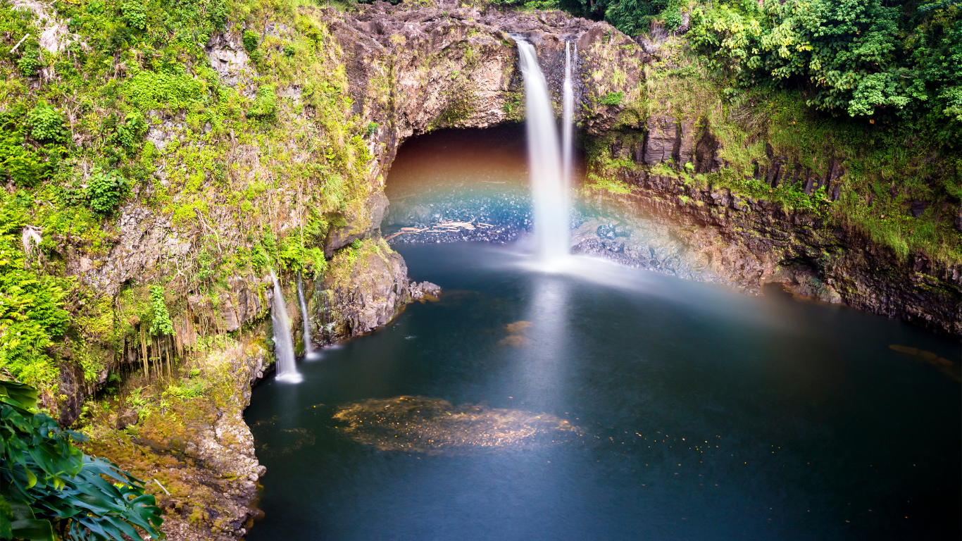 a waterfall with a rainbow cast from it's mist in Hilo called Rainbow Falls