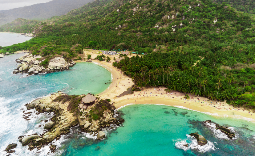 Ariel view of two beaches side by side with palm trees in the back and clear Caribbean waters in Tayrona National Park.