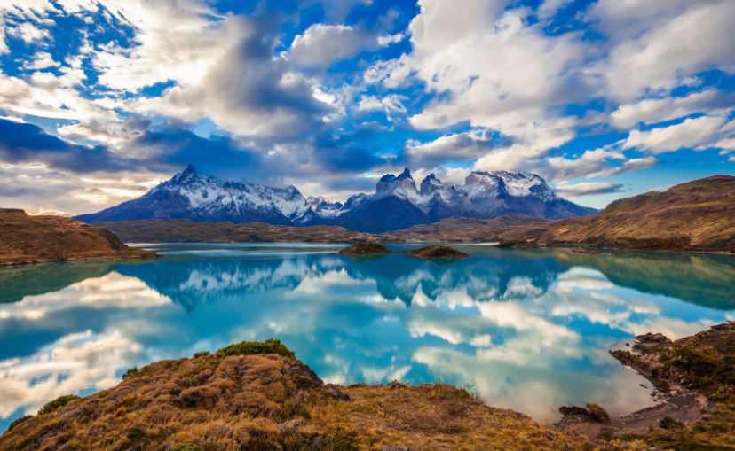 Clear emerald lake with jagged mountains in the background with the peaks covered in snow at Torres del Paine