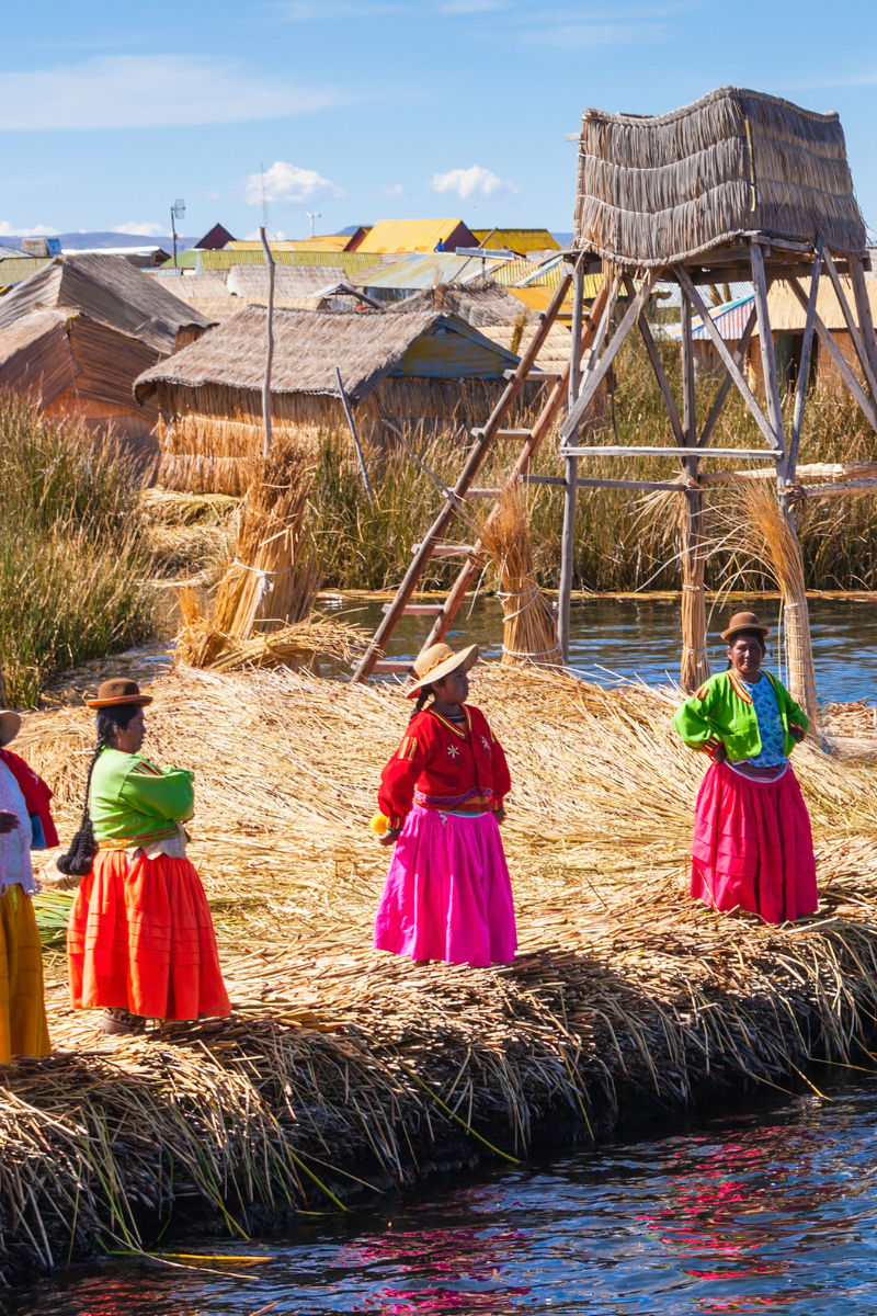 Uros women in colorful dresses on floating island made of reeds on Lake Titicaca