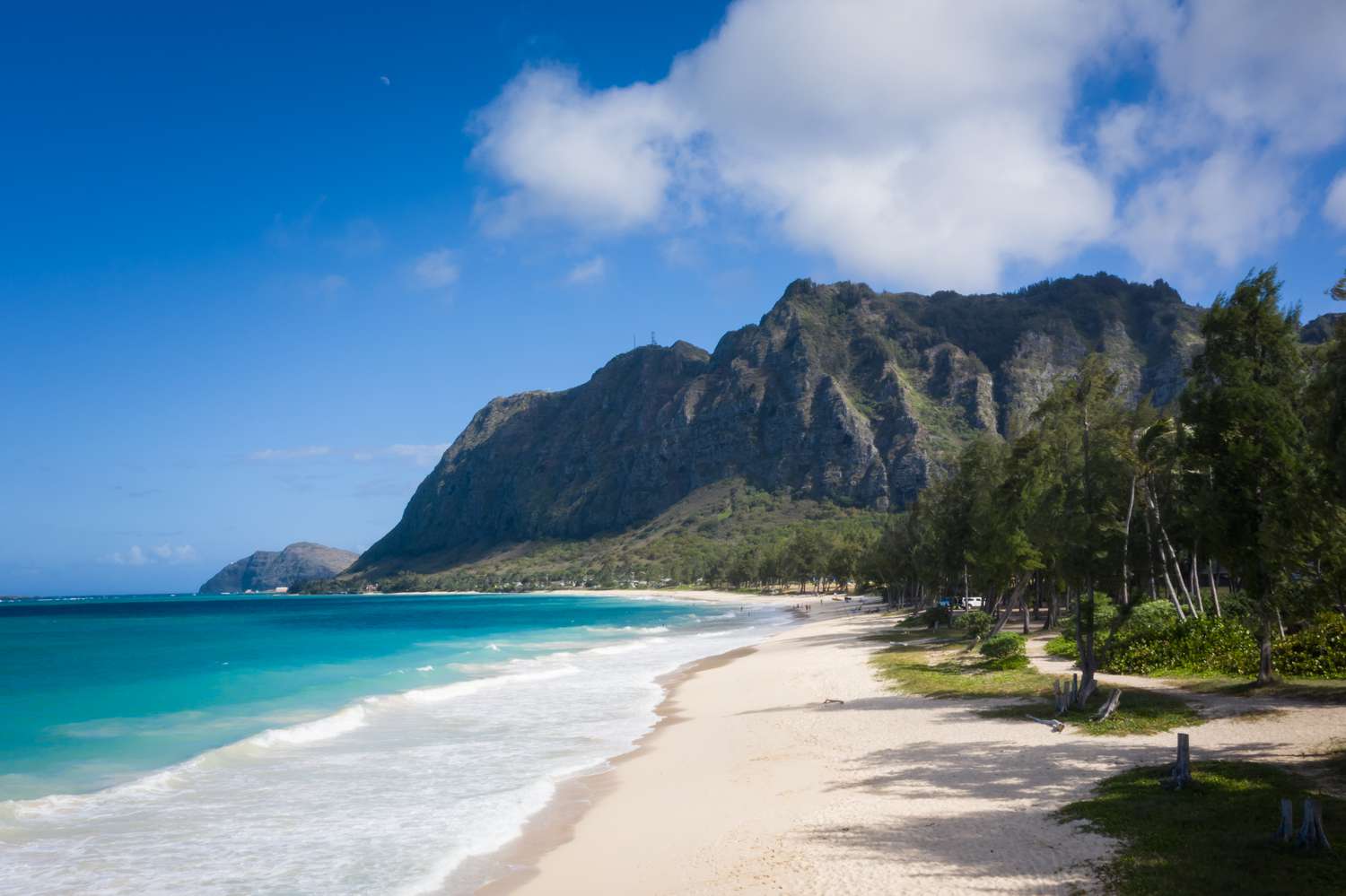 Waimanalo Beach with waves washing ashore with a mountain in the background.