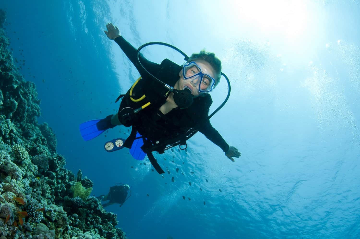 me scuba diving buck island wall in St. Thomas, with fish and coral reef around me and my friend in dive great swimming behind me. 