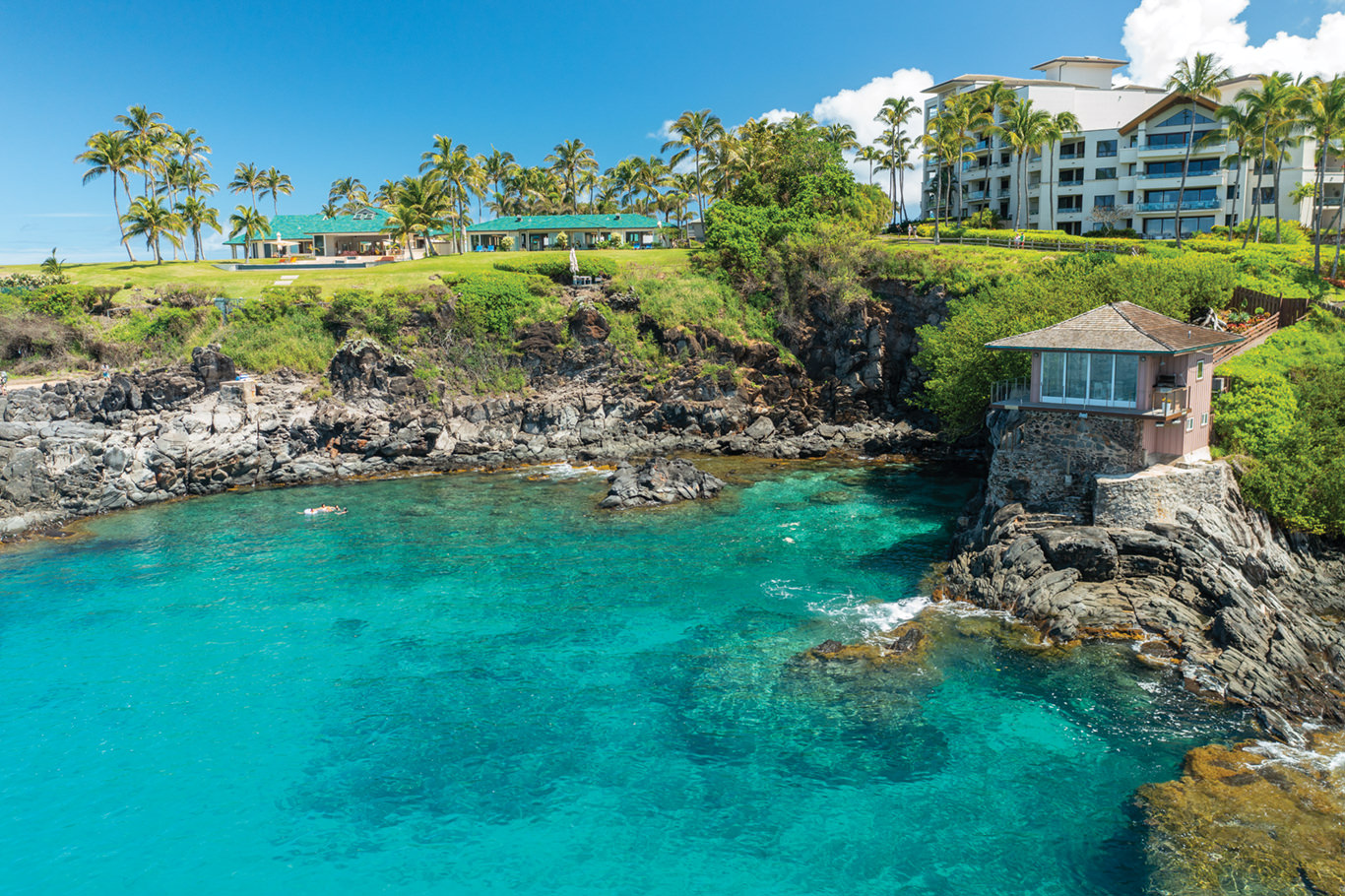 small building built on the side of a rocky cliff in Maui with clear waters below