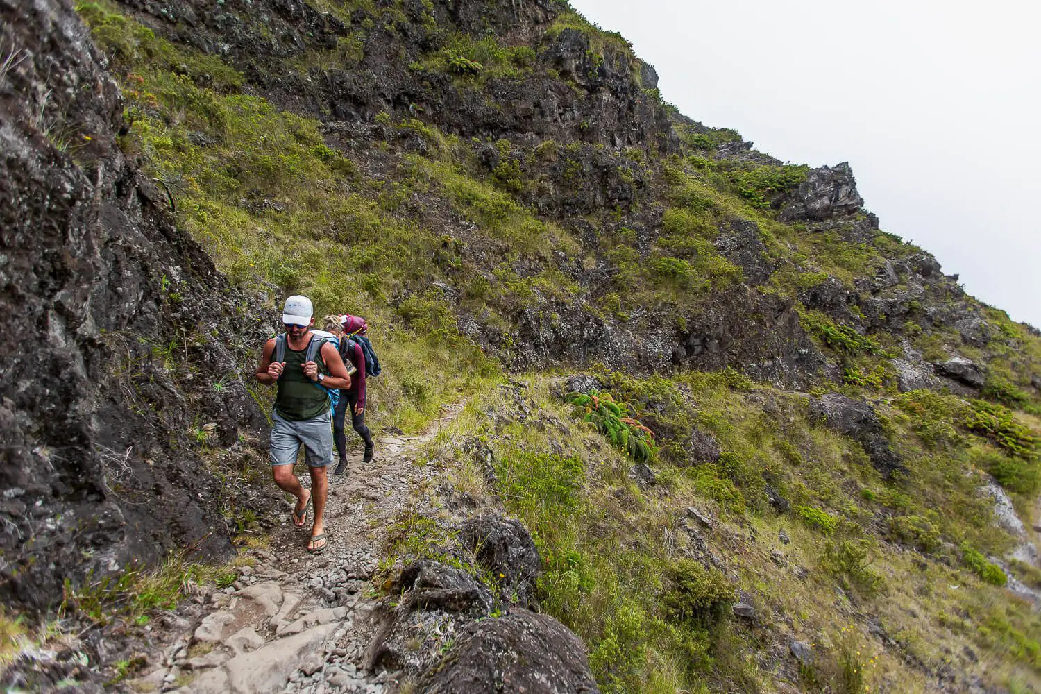 People walking along the cliff side of The Halemau’u Trail 