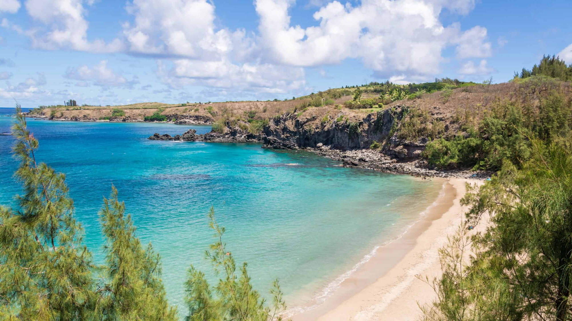 clear blue calm waters at the Slaughterhouse beach in Maui, with cliffs on each side.