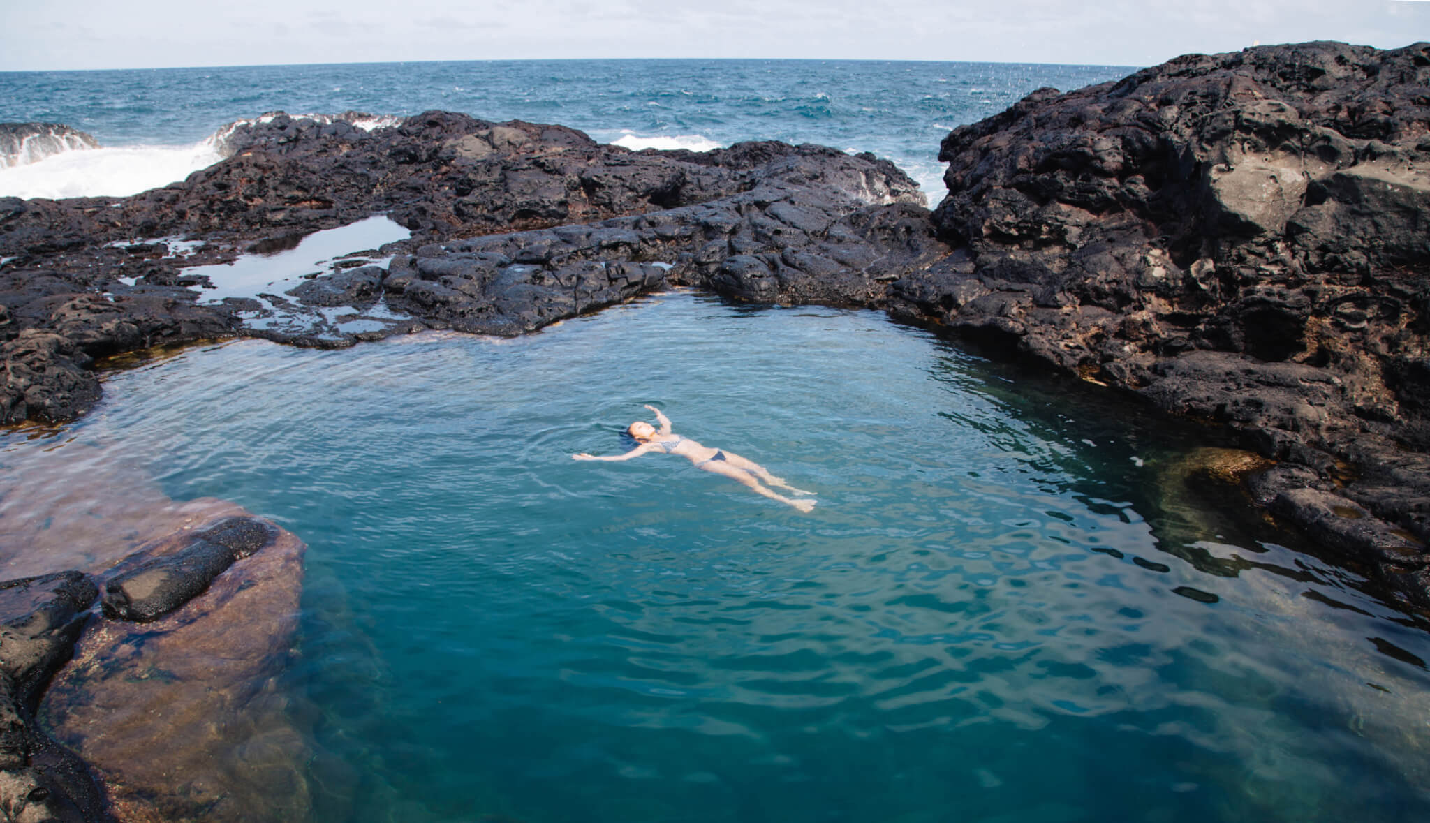 Olivine Pools In Maui with a woman floating in the center