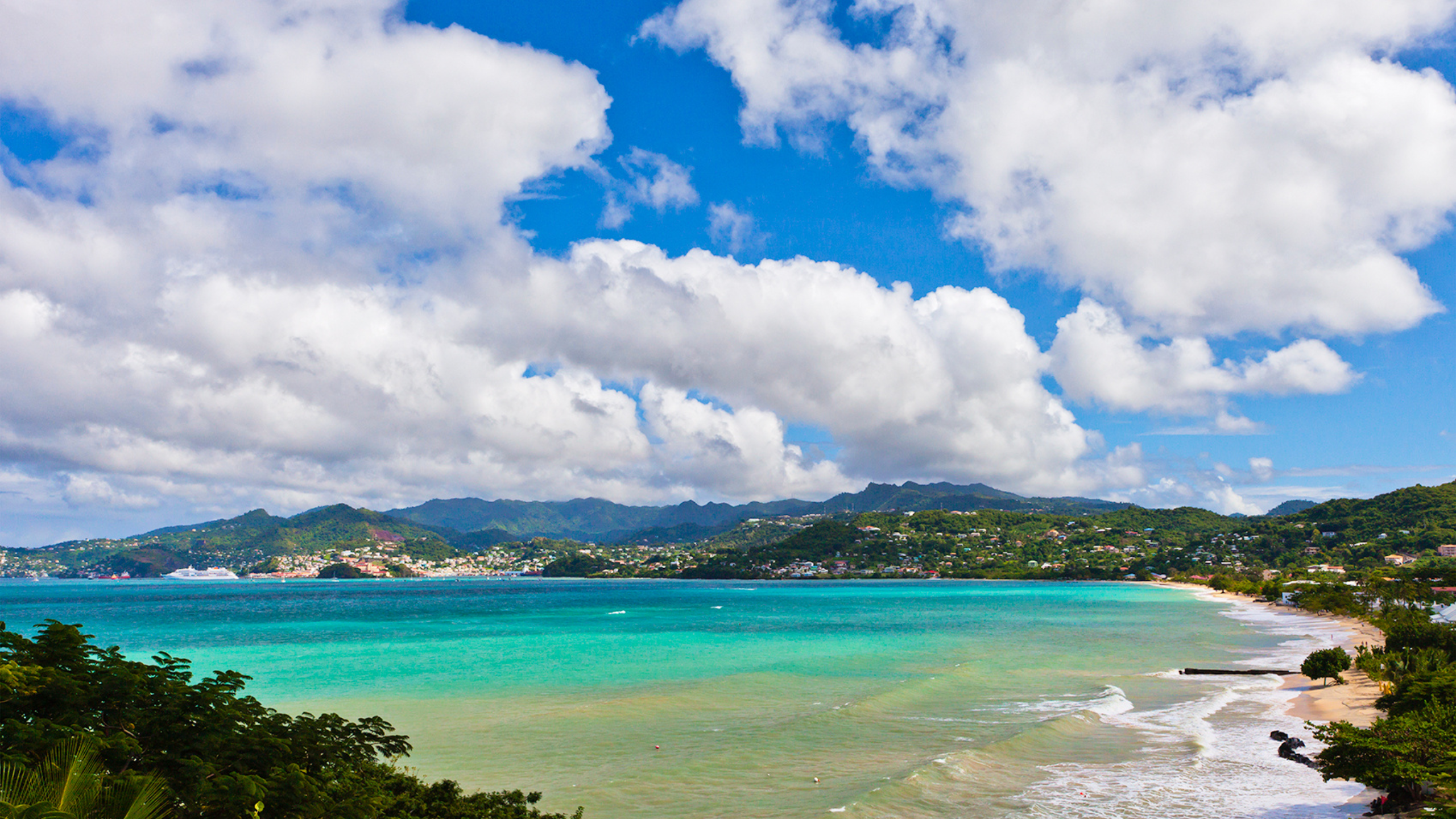 Overlooking Grand Anse Beach with clear blue waters, white sands and mountains in the background.