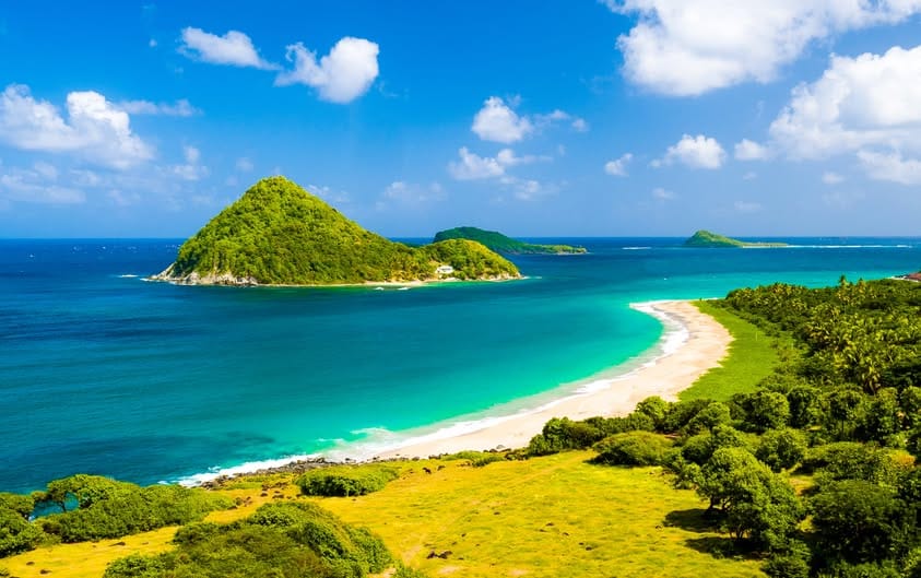 Levera Beach, Grenada has white sandy beaches, clear blue water with mountainous islands in the water just off the beach offering amazing views.