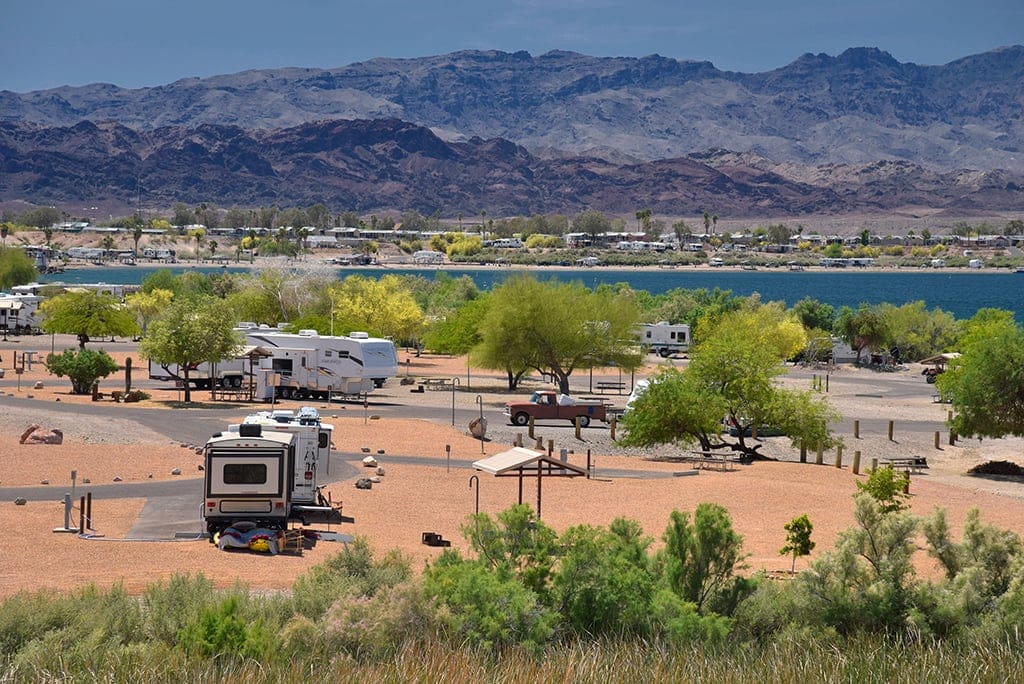 RV's parked at Lake Havasu State Park with mountains in the desert background and a lake in front of the mountains. 