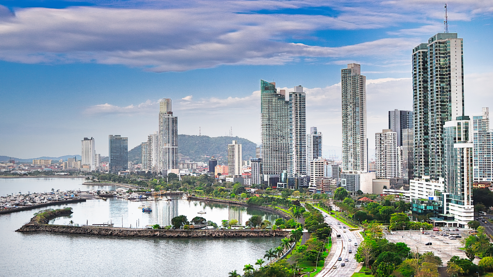 View of the skyline in Panama City with ocean and marina views below tall apartment buildings that overlook the ocean. 