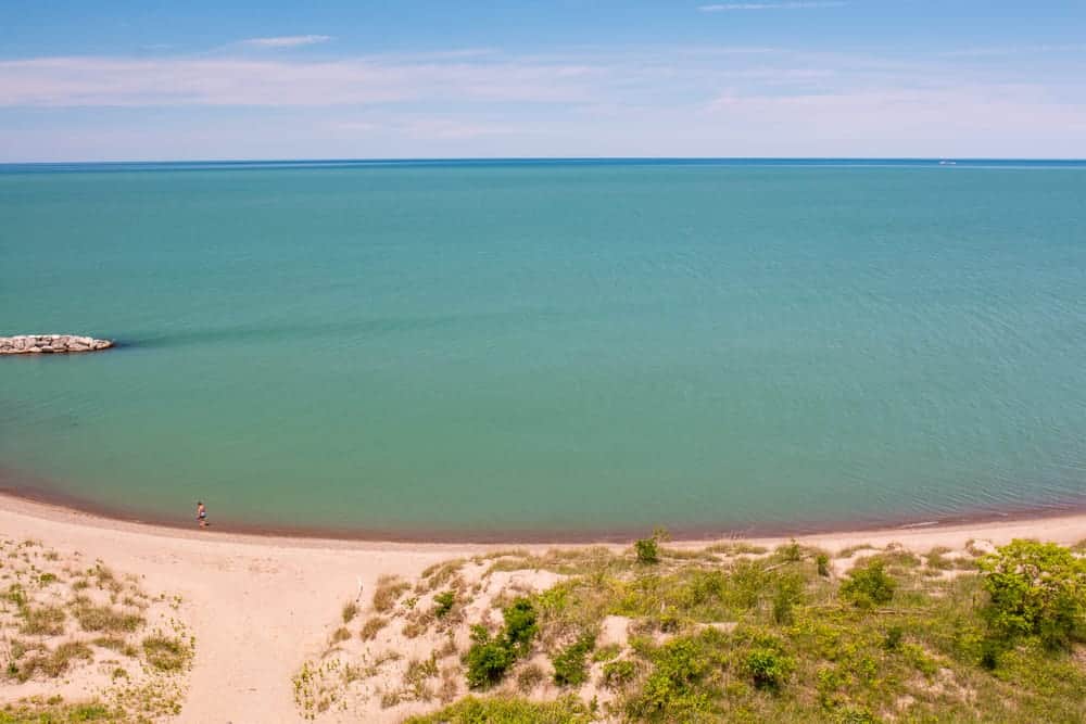 White sandy beach with calm clear waters with a blue tint at Presque Isle Park Beaches on lake superior.