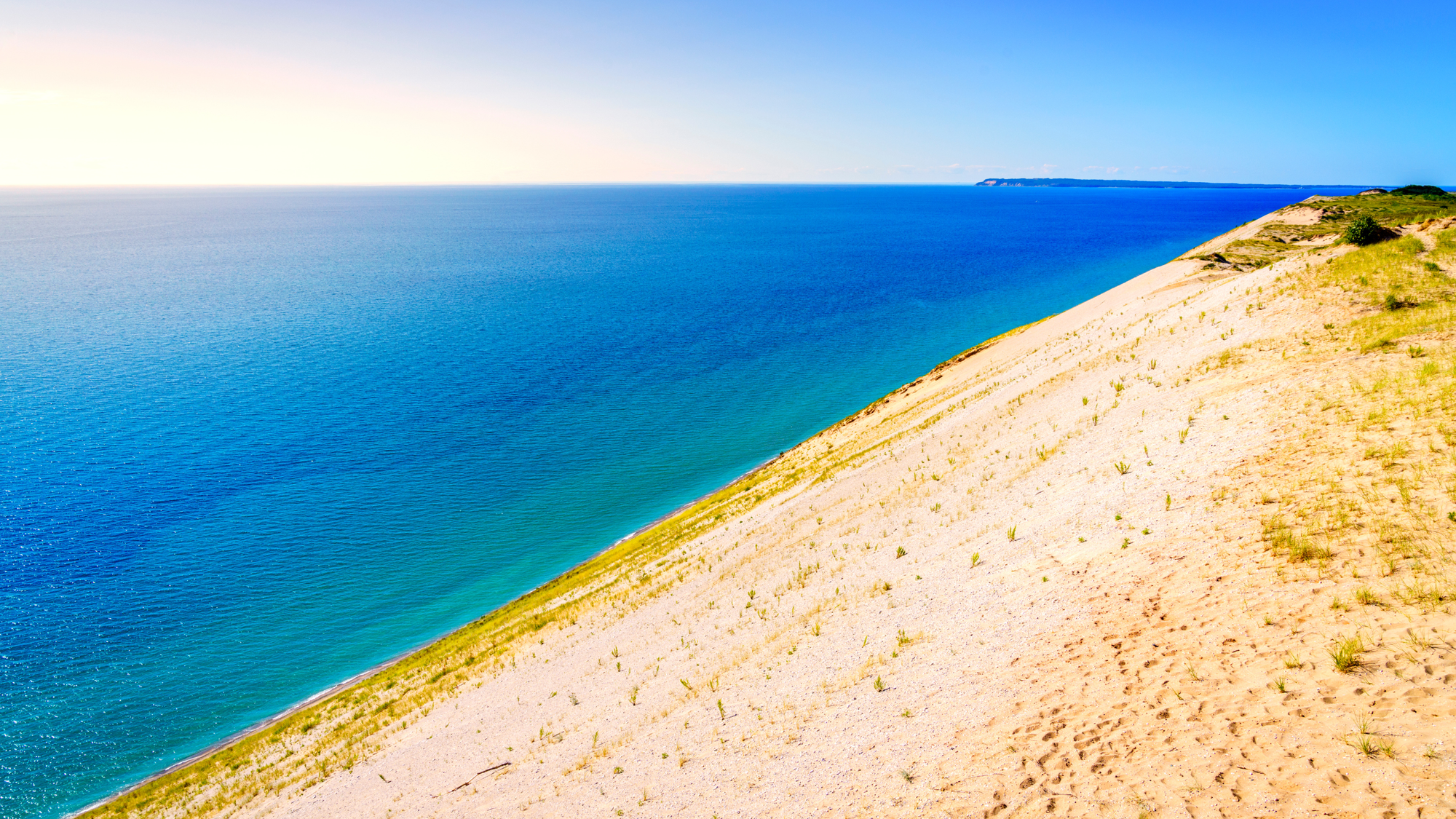 Large white sandy beach leading up to clear blue waters as far as you can see