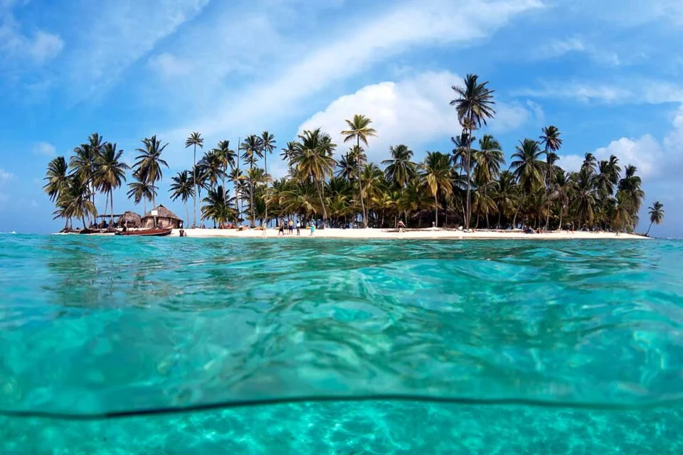 A view of the San Blas Islands from water level where the camera is slightly in the water allowing you to see both in the water and the island. 