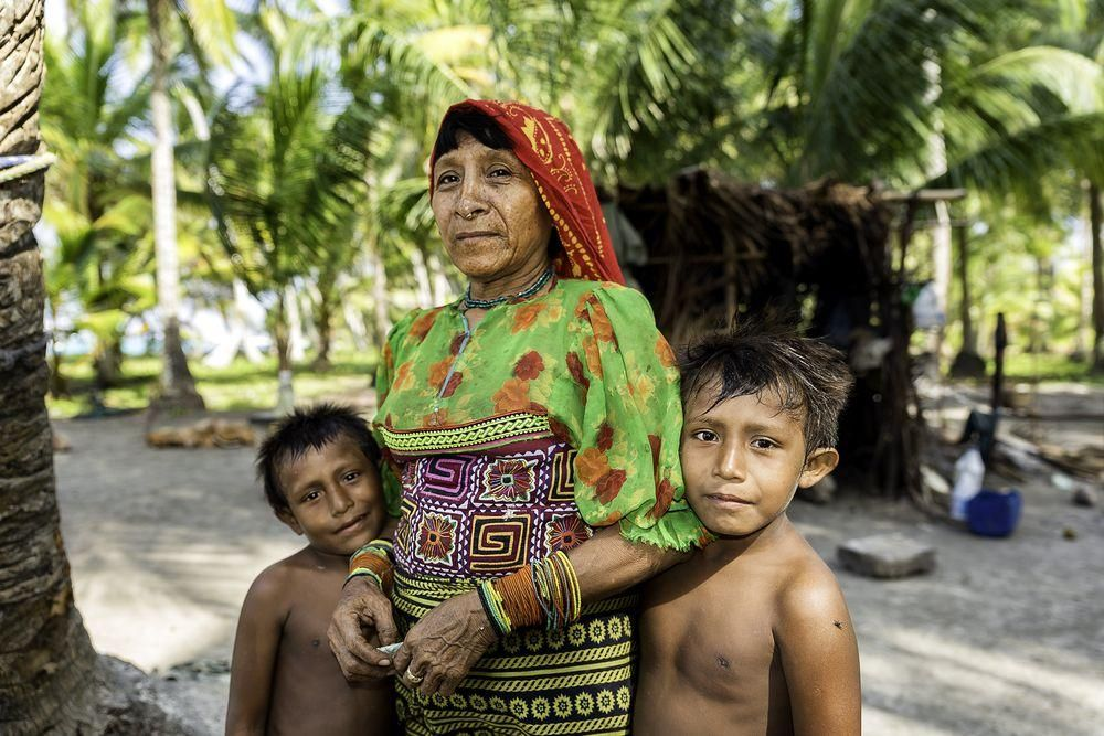 Two little Kuna tribe boys and their mother stand for a photo on the island they call home. 