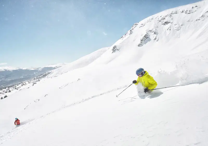 A person in yellow ski suit skiing in really deep powder at Breckenridge Ski Resort.