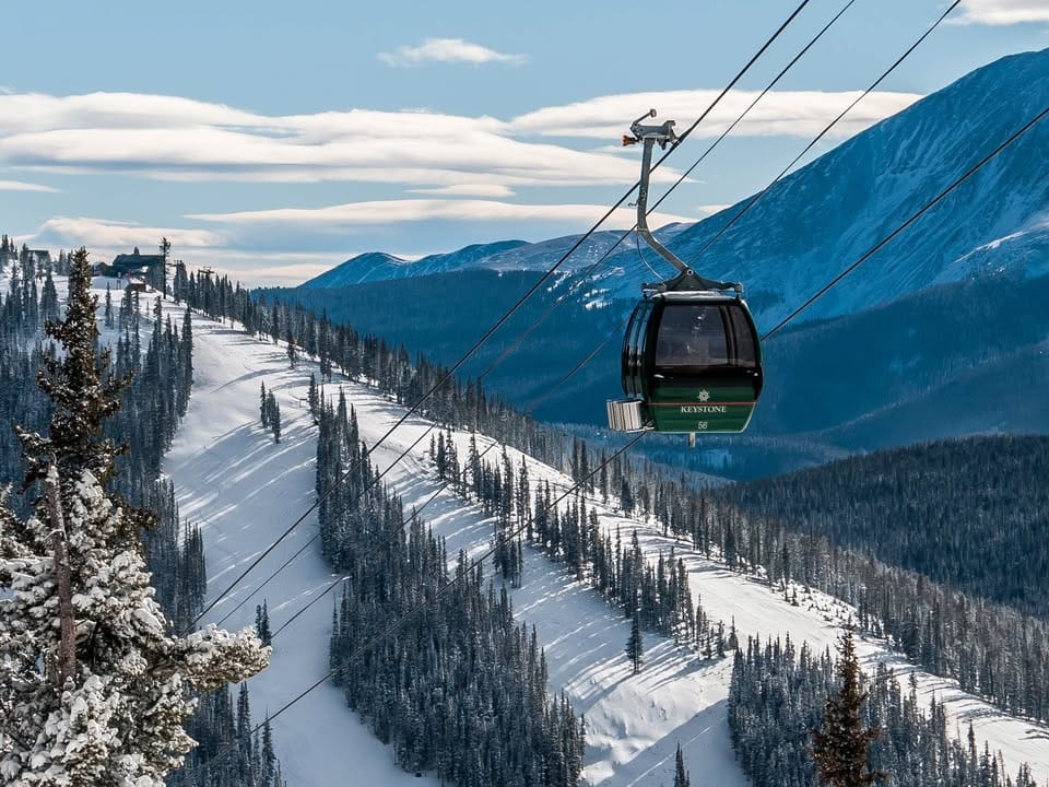 Single Gondola going up the mountain at Keystone Ski Resort with ski runs seen below it.