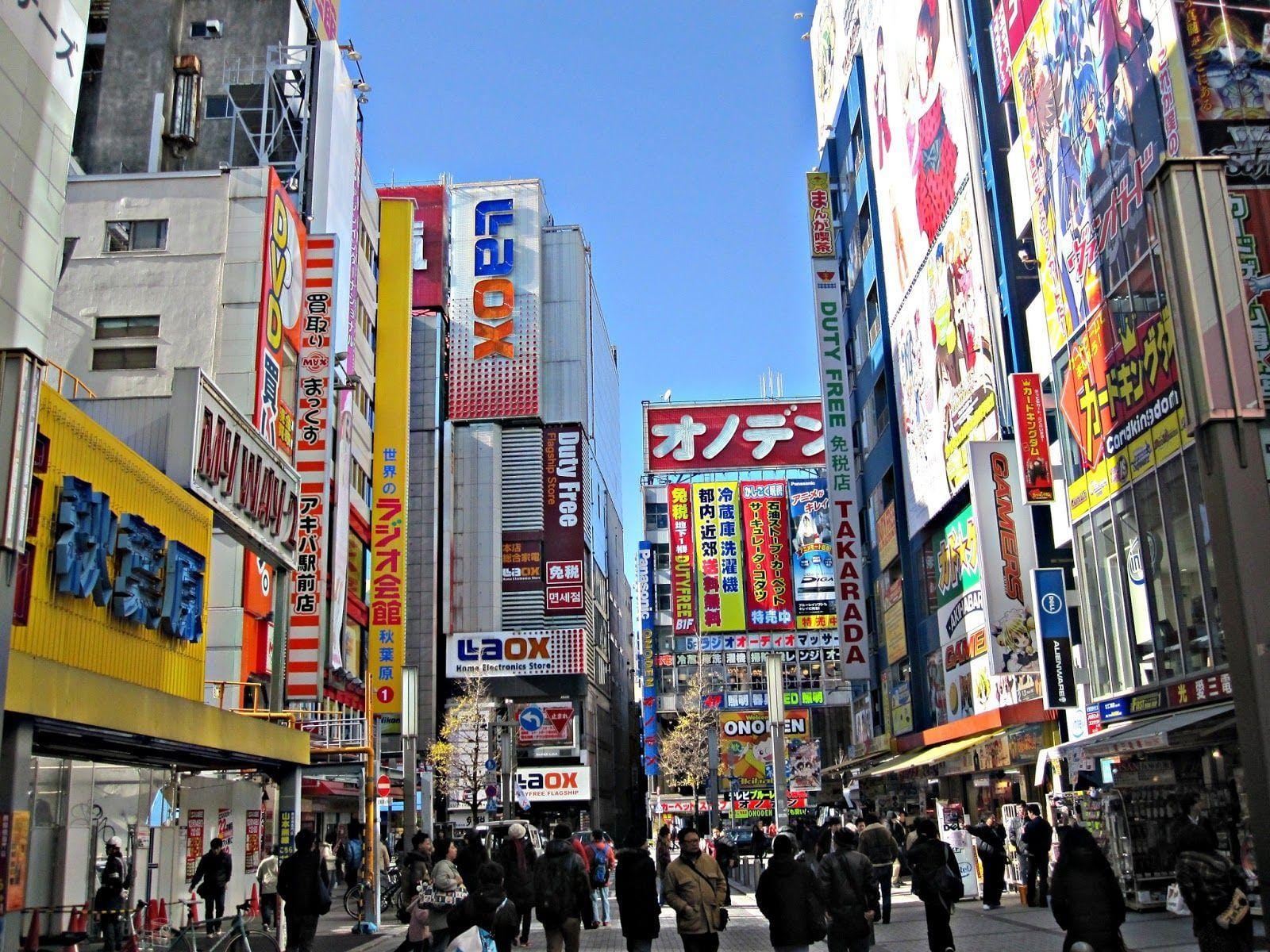 people walking the streets surrounded by brightly colored buildings in Electric Town, in Akihabara