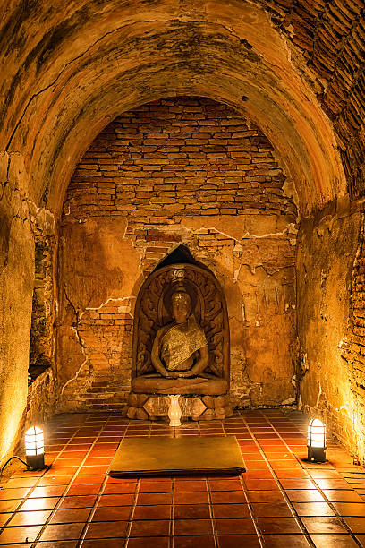 two lights on the ground lighting up a ancient Buddha statue inside a brick underground tunnel at the Wat Umong Suan Putthatham Temple near Chiang Mai.