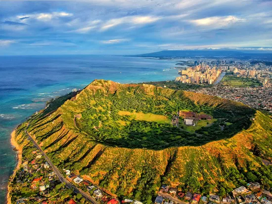 Ariel view of a giant old inactive volcanic crater that is now overgrown tropical plants and trees. 