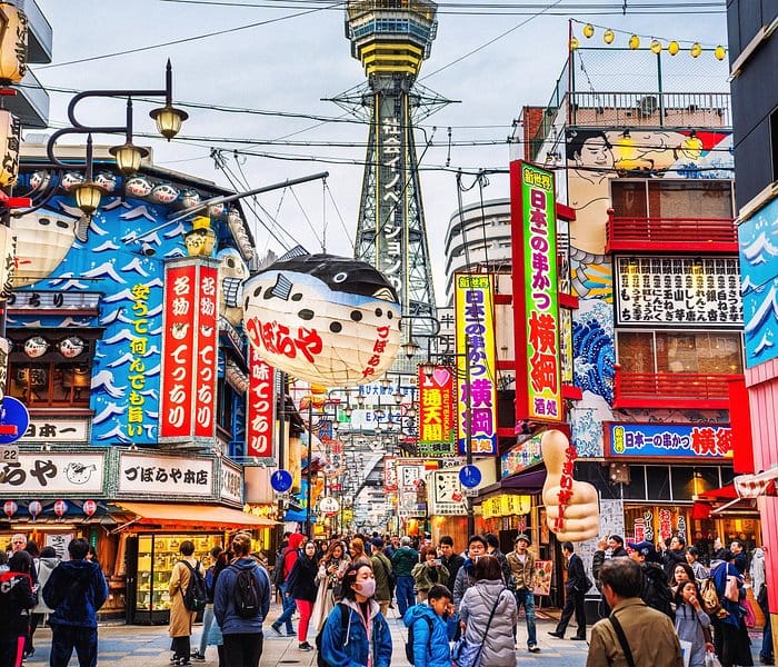 People walking the streets of the and exploring the Shinjuku area of Tokyo where all the buildings are covered in bright colors and neon signs. 